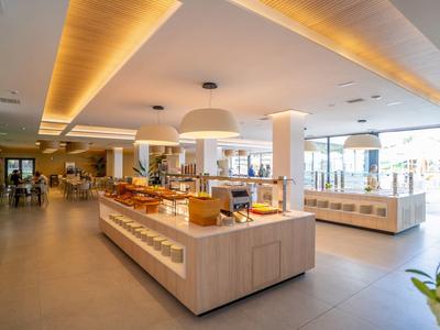 Nowoczesny, jasny bufet w hotelowej restauracji z dużymi oknami i ciepłym oświetleniem.