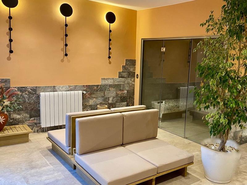 Modern seating area with beige upholstery, stone wall, and large glass sliding doors.