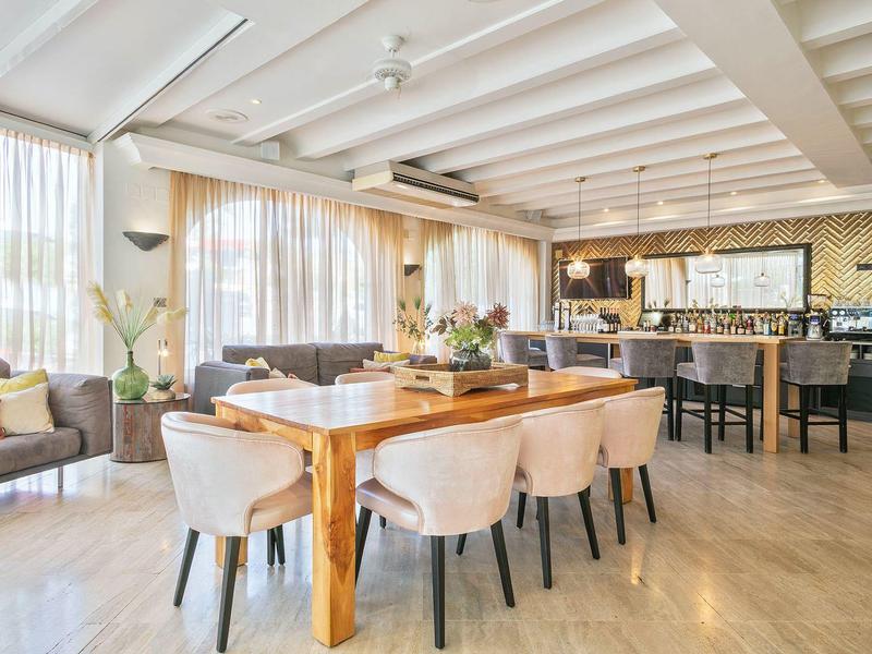 Bright, modern dining room with wooden table, upholstered chairs, and large windows.