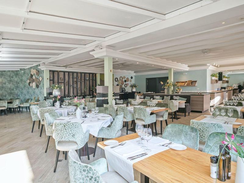 Bright restaurant with set tables and green chairs in stylish interior.