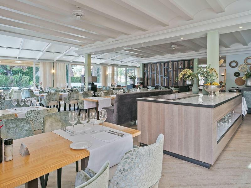 Brightly furnished restaurant area with set tables and cozy atmosphere in a hotel.