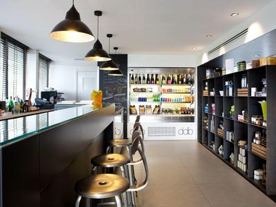 Espace bar d'hôtel moderne avec tabourets, étagères et station de boissons éclairée.