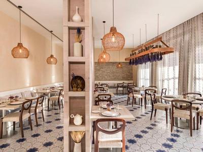 Restaurant lumineux avec mobilier en bois moderne, suspensions et sol carrelé à motifs