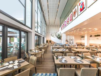 Salle à manger moderne avec grandes fenêtres et tables élégamment dressées dans une ambiance lumineuse.