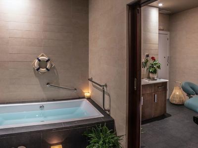 Salle de bain moderne avec baignoire et espace bien-être adjacent avec table de massage.