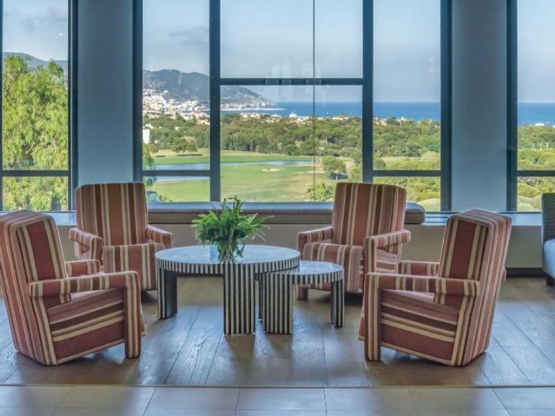 Coin salon confortable avec fauteuils rayés devant de grandes fenêtres donnant sur la mer.