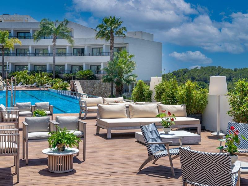 Espace piscine d'hôtel moderne avec sièges confortables et fleurs sur terrasse en bois.