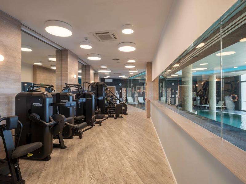 Salle de sport moderne avec équipements d'entraînement et mur de miroirs dans un hôtel