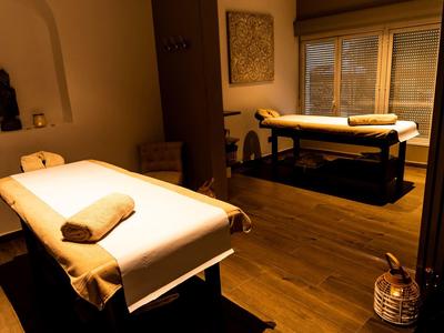 Cozy massage room with two tables, warm lighting, and wooden floors.