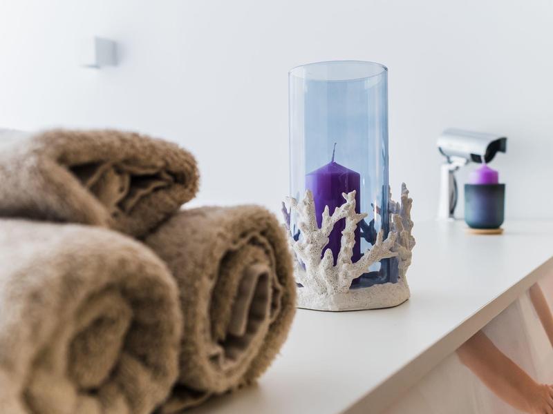 Rolled brown towels and a decorative candle holder on a white surface, cozy spa setup.