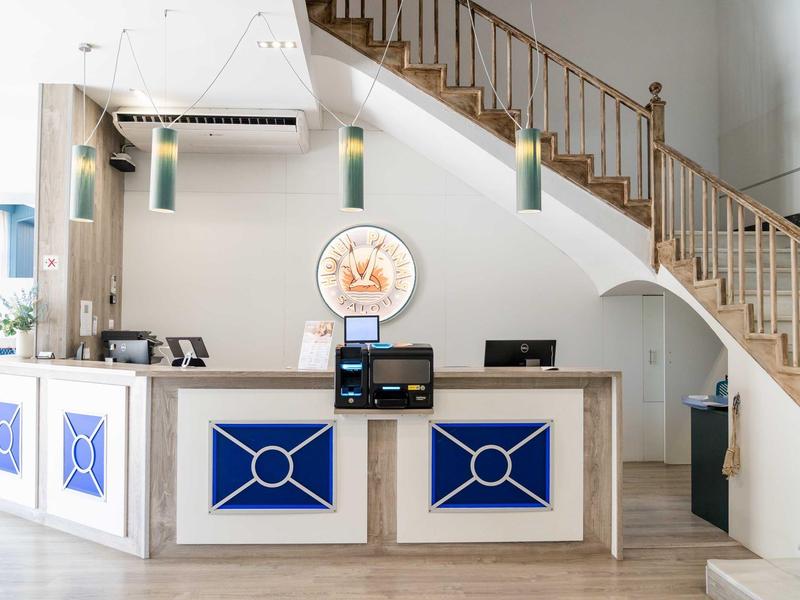 Hotel reception with blue and white counter under a staircase.