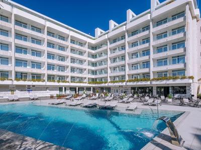 Moderner Hotelkomplex mit mehrstöckigem Gebäude, großem Schwimmbecken und Liegestühlen.