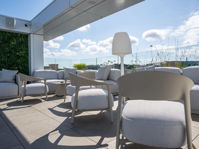 Muebles de terraza modernos con tapicería blanca en una terraza de hotel con vista al puerto deportivo.