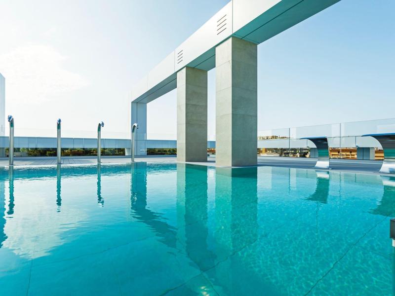 Piscina moderna al aire libre con agua azul clara y arquitectura elegante en un día soleado.