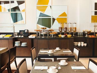 Helles Frühstückszimmer mit gedeckten Tischen und Buffet in modernem Design.