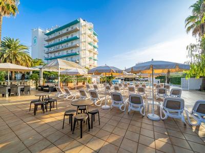 Hotel terrace with sun loungers, umbrellas, and tables in sunny weather