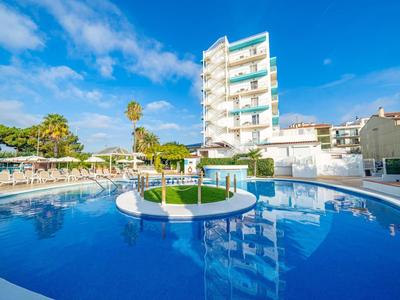 Modern hotel pool with round basin, island, and sun loungers under clear sky