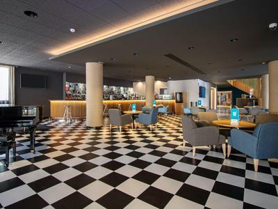 Moderní hotelový lounge s černo-bílou šachovnicovou podlahou a křesly.