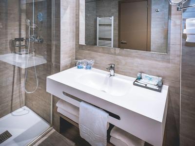 Moderní koupelna s bílým umyvadlem, zrcadlem, sprchou a fénem