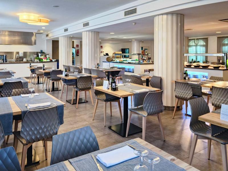 Světla, moderní restaurace s mnoha stoly a šedými čalouněnými židlemi v hotelu.