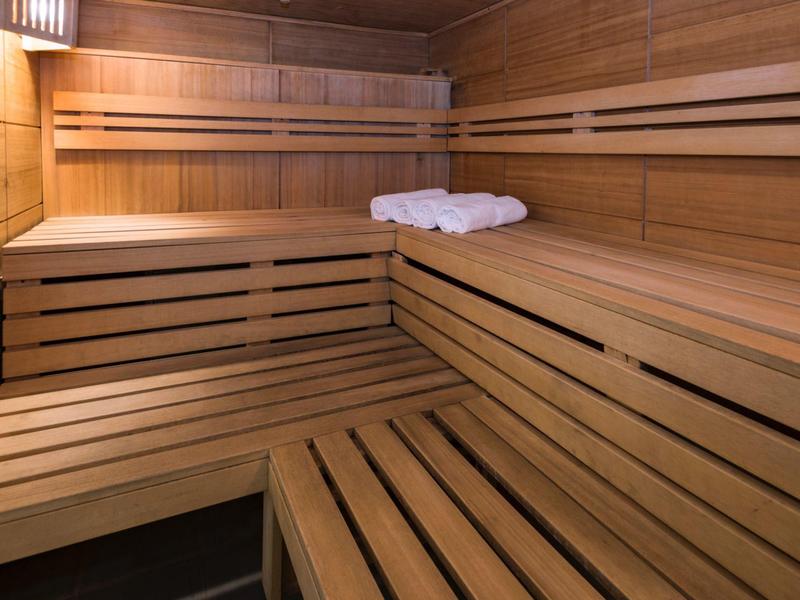 Interiér sauny s dřevěnými lavicemi a dvěma bílými ručníky.