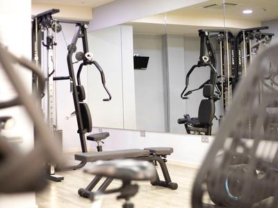 Palestra con varie attrezzature per esercizi e parete a specchio sullo sfondo.