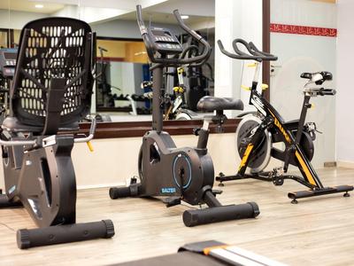 Spazio interno con cyclette e bici da spinning su pavimento chiaro.