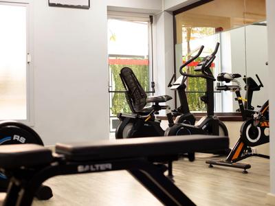 Palestra luminosa con cyclette e panca da allenamento davanti a grandi finestre.