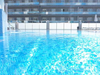 Piscina limpida con acqua blu davanti a un edificio alberghiero multipiano