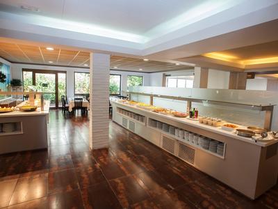 Area buffet con offerta di cibo variegata e pavimento in legno scuro in un hotel moderno.