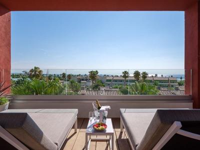 Balcone con due lettini, tavolo e vista sul mare e sulle palme
