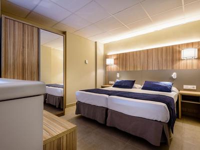 Chambre d'hôtel moderne avec lit double, tables de chevet et grand miroir mural.