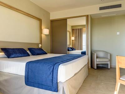 Chambre d'hôtel moderne avec grand lit, couvre-lit bleu, chaise et armoire avec miroir.