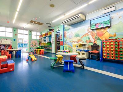 Bunter Kinderspielraum mit Tischen, Stühlen und Wanddekoration in einem Hotel.