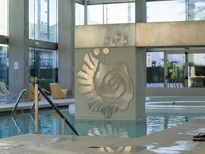 Moderner Innenpool mit großen Fenstern und dekorativer Wandgestaltung in Hotelumgebung.