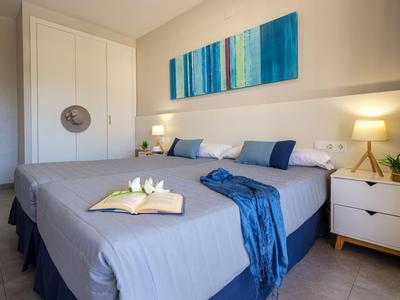 Modern eingerichtetes Hotelzimmer mit großem Bett, Nachttischen und abstraktem blauen Wandbild.
