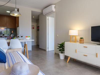 Modern eingerichtetes Wohnzimmer mit Sofa, Esstisch und TV in einer Hotelwohnung.