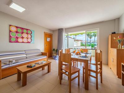 Heller Wohnbereich mit Holzmöbeln, Esstisch, Sofa und Zugang zu einer Terrasse mit Blick aufs Meer.