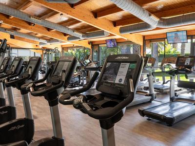 Modern ausgestatteter Fitnessraum mit Cardio-Geräten und großer Fensterfront in einem Hotel.