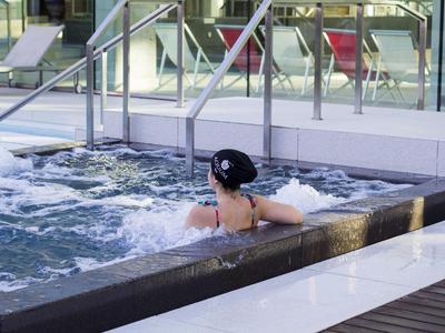Person entspannt im sprudelnden Whirlpool in moderner Hotelumgebung.