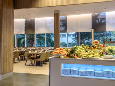Buffetbereich in einem modernen Hotelrestaurant mit frischem Obst und gedeckten Tischen.