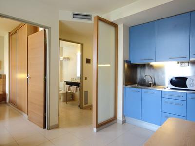 Moderner Küchenbereich mit blauen Schränken, offenem Eingang zum Bad und hellen Wänden