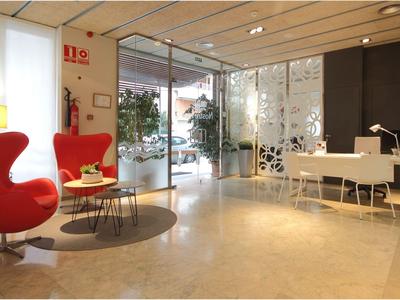 Moderner Hotellobby mit roten Sitzstühlen, Empfangstresen und hellen Marmorboden.