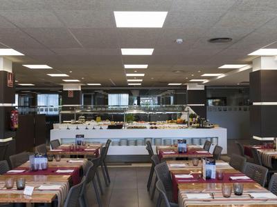 Innenansicht eines modernen Hotelrestaurants mit gedeckten Tischen und zentraler Buffettheke.