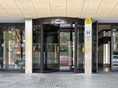 Eingangsbereich eines Hotels mit Glasöffnung, Säulen und Sicht auf die Straße.