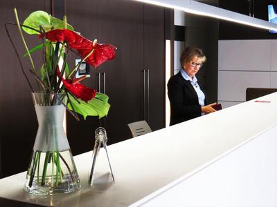 Moderner Hotellobby-Empfang mit weißem Tresen und roter Blumendekoration.