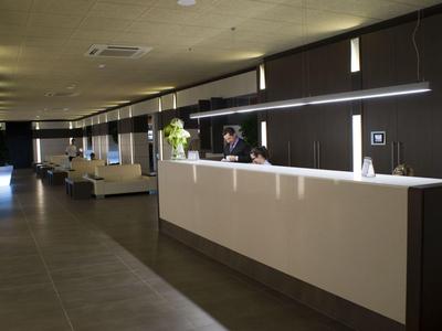 Modern eingerichteter Hotel-Empfang mit großem weißen Tresen und stilvoller Beleuchtung.