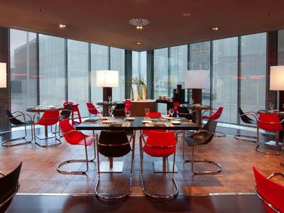 Restaurant d'hôtel moderne avec des chaises rouges et de grandes fenêtres panoramiques en milieu urbain.