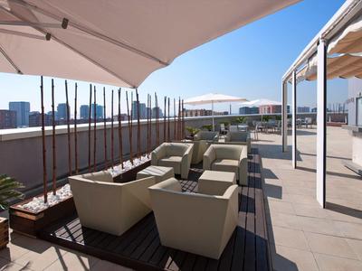 Terrasse sur le toit avec fauteuils modernes sous parasols et vue sur la ville.