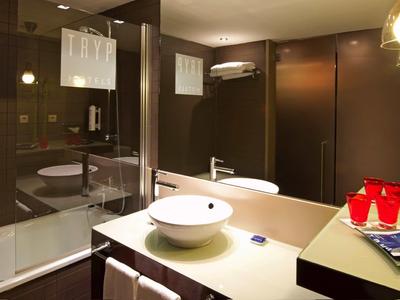 Salle de bain moderne avec lavabo blanc, miroir et baignoire avec cloison en verre